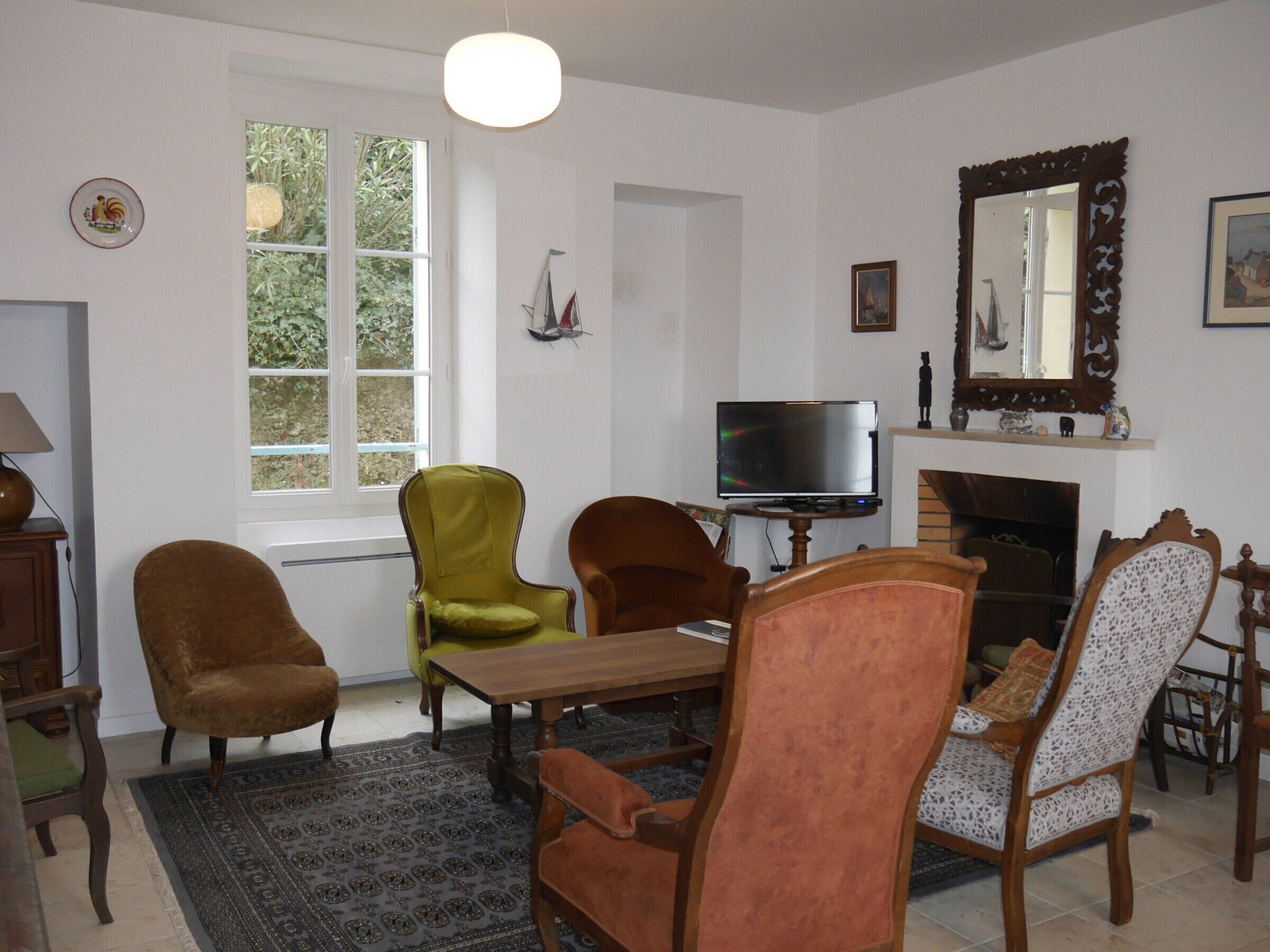 A living room with a wooden table, four chairs, a television, and a fireplace.