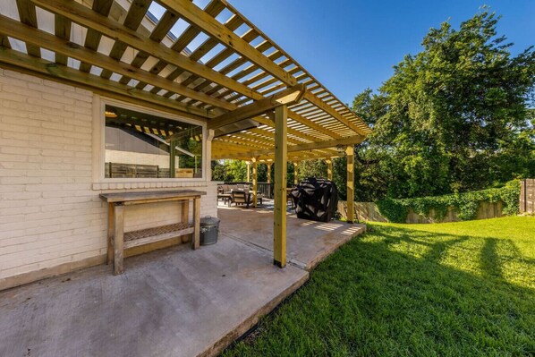 A covered patio area with a barbecue grill, outdoor seating, and a brick wall. - South ATX Home Sauna, Parking, Cowboy Pool (Austin)