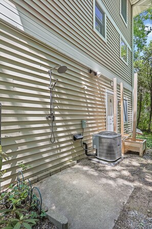 A house with exterior walls, a door, a window, a hose, an air conditioning unit, and a small wooden structure. - Beachfront Haven | Grill • Hot Tub • Sunset Views! (South Haven)