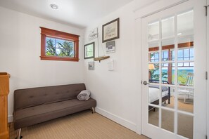 A room with a sofa, a door leading to a balcony, and framed pictures on the wall. - Beachfront Haven | Grill • Hot Tub • Sunset Views! (South Haven)