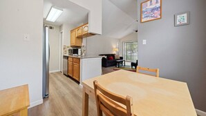 Ett kompakt bostadsutrymme med ett kök, en matplats och en liten sittgrupp.
