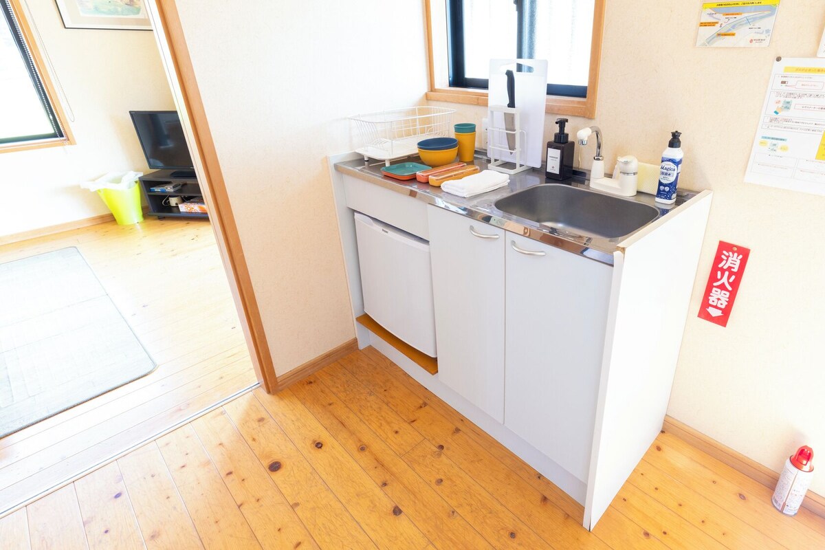 Cocina compacta con lavamanos, armarios y una ventana sobre la encimera.