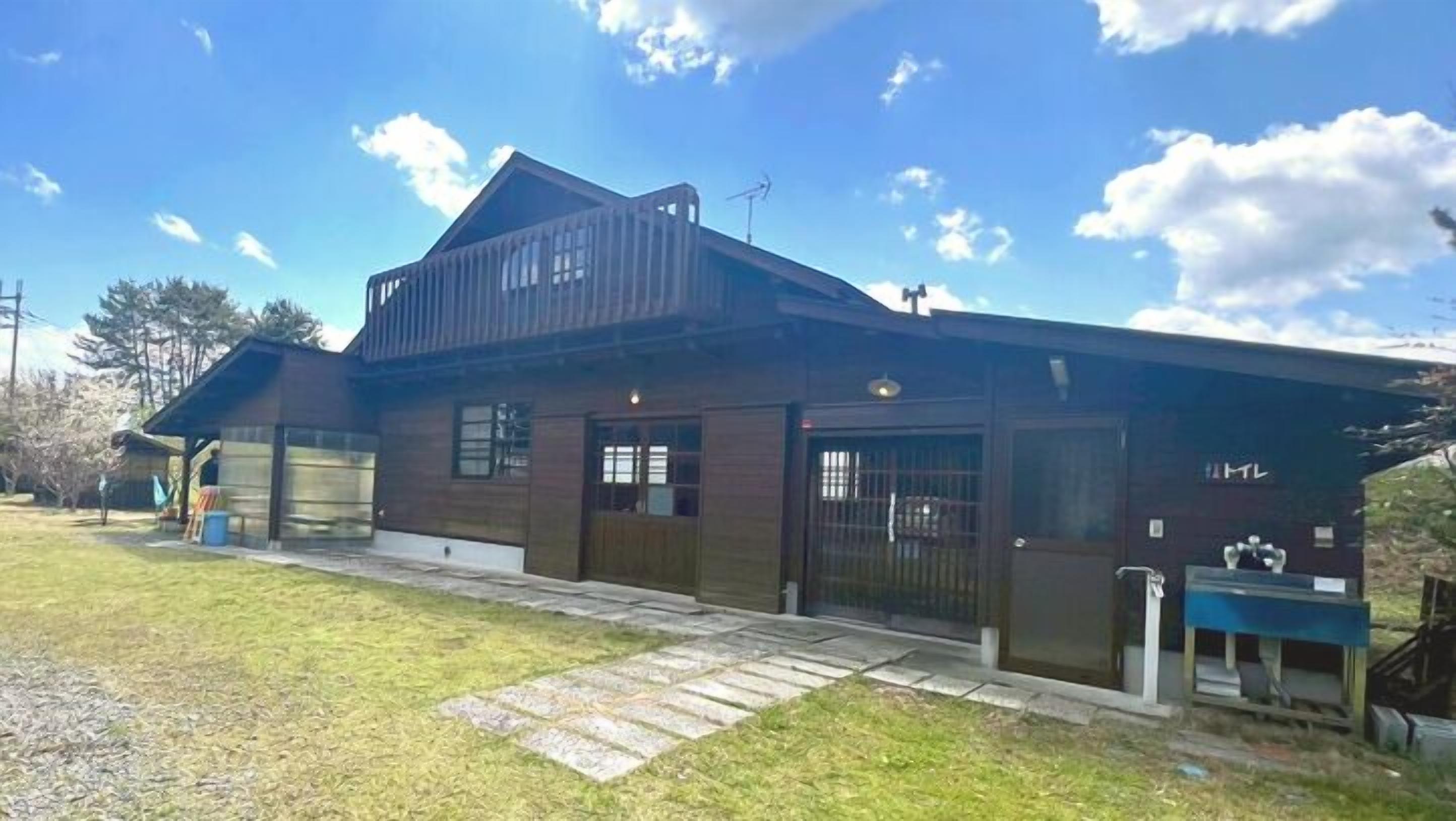 A two-story house with a garage, a covered porch, and a small outdoor seating area.