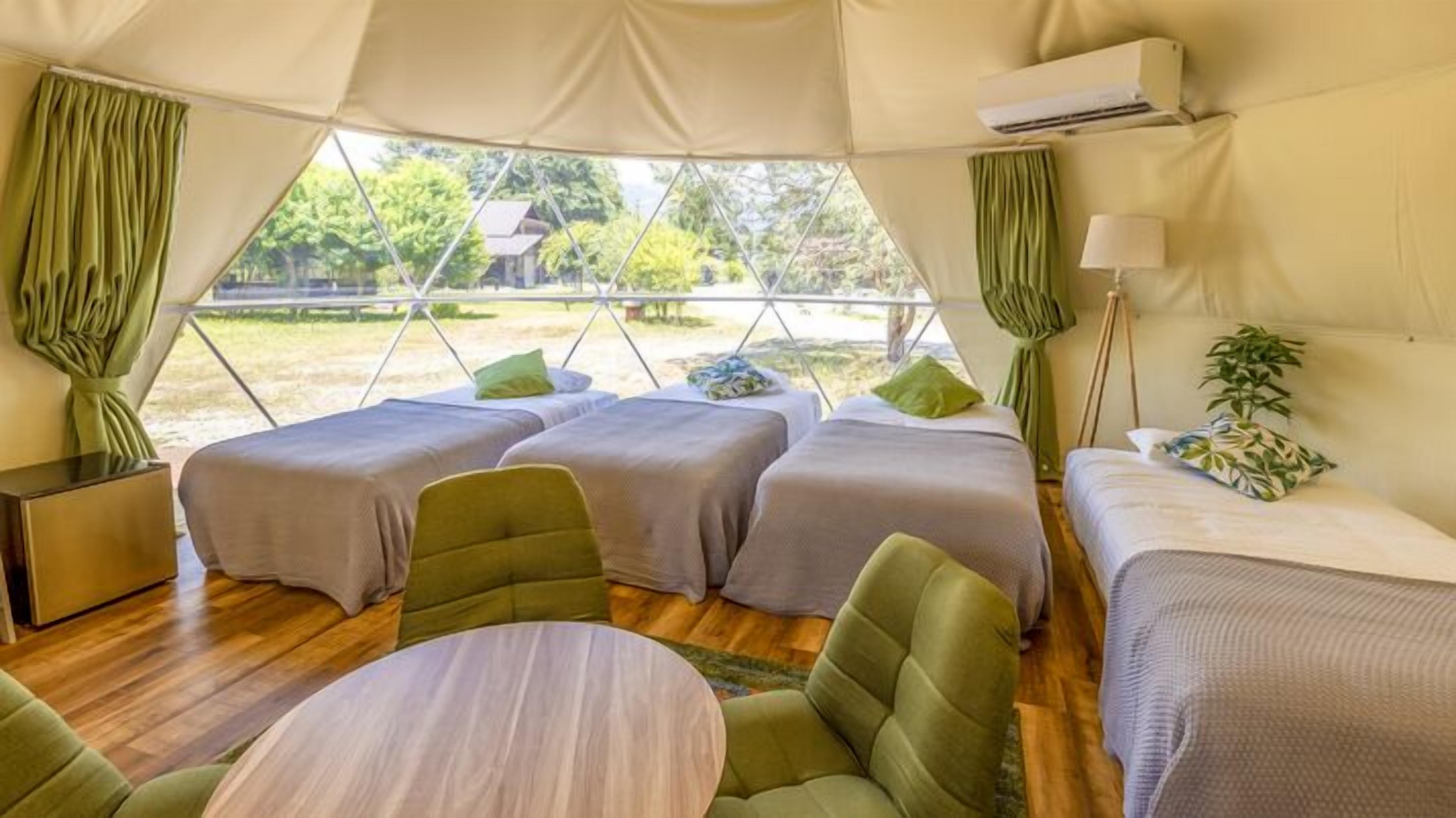 A tent with two beds, a table, and a lamp.