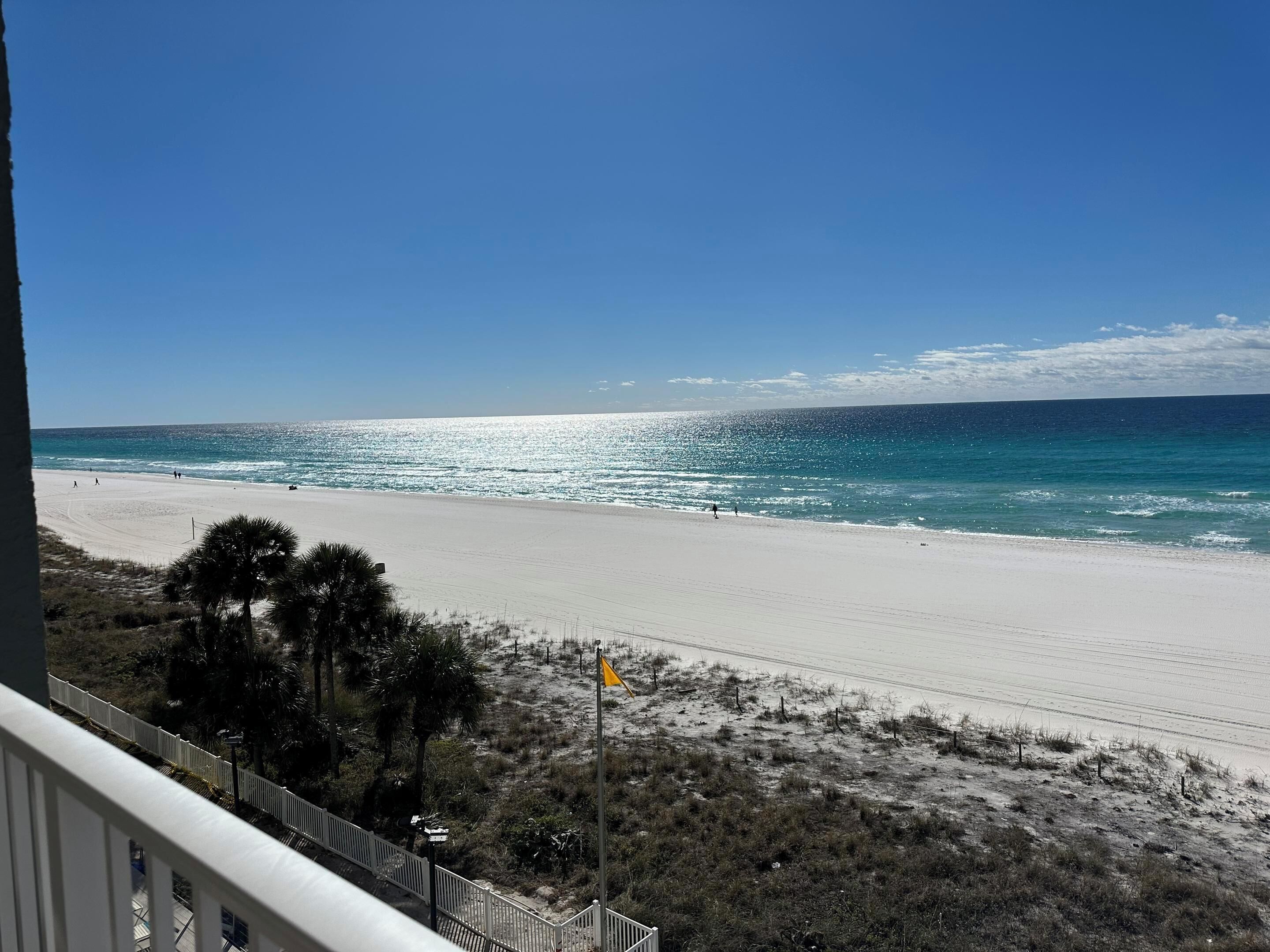 A beach with a clear view of the ocean and a few people walking along the shore.