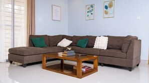 Una sala de estar con un sofá modular, una mesa de centro y dos láminas botánicas enmarcadas en la pared.