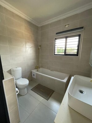 A bathroom with a toilet, bathtub, and sink.