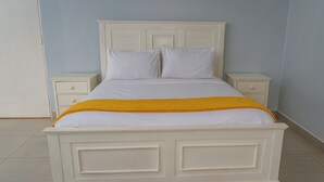 A white bed with a yellow throw blanket, two nightstands, and a white dresser. - Large spacious family friendly 4 bedroom home in Lilongwe (Lilongwe)