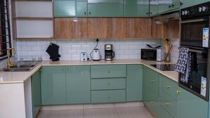 A kitchen with green cabinets, a microwave, a coffee maker, and a sink. - Large spacious family friendly 4 bedroom home in Lilongwe (Lilongwe)