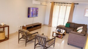 A living room with a sofa, two patterned chairs, a coffee table, a TV, and a window with curtains. - Large spacious family friendly 4 bedroom home in Lilongwe (Lilongwe)