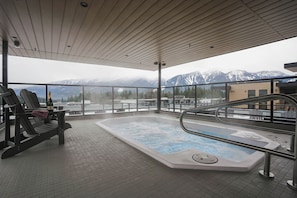 A hot tub on a balcony with a view of snow-capped mountains. - Veldt Haus (Revelstoke)