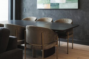 A modern dining area with a dark table and velvet chairs. - Veldt Haus (Revelstoke)