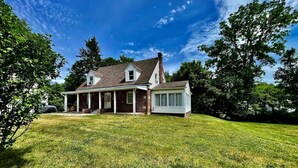 A two-story house with a covered porch and a separate garage. - Enclosed Hot Tub, King Bed, 3 bdrm, close to town (Ellenville)