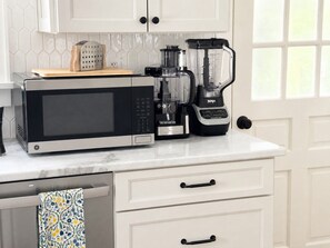 Une cuisine équipée d’un four à micro-ondes, d’une machine à café et d’un mixeur, le tout posé sur le plan de travail.