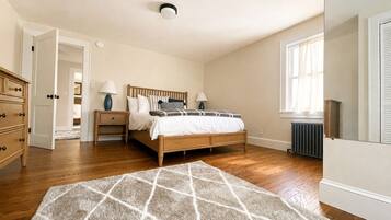 A bedroom with a bed, bedside tables, a dresser, and a radiator.