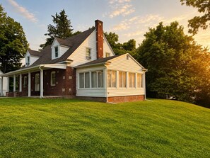 Une maison à deux étages avec un porche abrité et une grande pièce dotée de larges fenêtres.