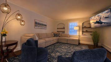 A living room with a sectional sofa, two armchairs, a round coffee table, and a floor lamp.
