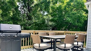 An outdoor patio with a grill, wicker chairs, and a table. - Enclosed Hot Tub, King Bed, 3 bdrm, close to town (Ellenville)