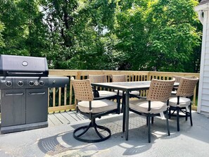 Une terrasse extérieure avec un barbecue, des chaises en osier et une table.