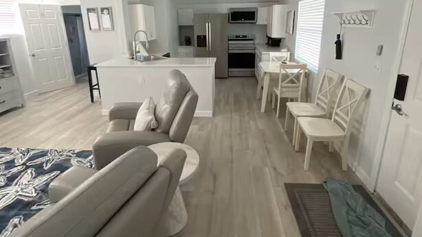 A modern living room with a sofa and chairs, a dining area with a table and chairs, and a kitchen with appliances. - Cottage on Dona Bay (Nokomis)