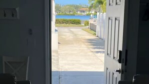 A doorway leading to a covered outdoor area with a view of a body of water and greenery. - Cottage on Dona Bay (Nokomis)