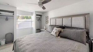A bedroom with a large bed, a ceiling fan, a wardrobe, and a window with blinds. - Cottage on Dona Bay (Nokomis)