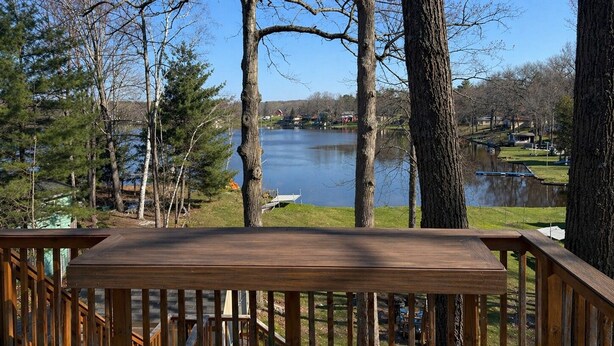 A wooden deck with a view of a lake and surrounding trees. - Lakefront Retreat w/ Private Dock • Sleeps 8 (Mecosta)