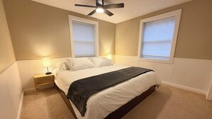 A bedroom with a bed, nightstands, a ceiling fan, and two windows with blinds. - Lakefront Retreat w/ Private Dock • Sleeps 8 (Mecosta)