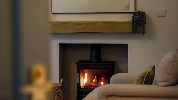 Ein gemütliches Wohnzimmer mit Kamin, einer Couch und einer Wandlampe.