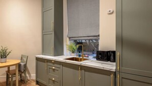 Eine kleine Küche mit Spüle, einem Fenster mit Jalousie und einem Essbereich mit Tisch und Stühlen.
