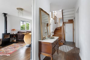 Ein Zimmer mit Kamin, einer Couch, einem großen Spiegel und einer Treppe.