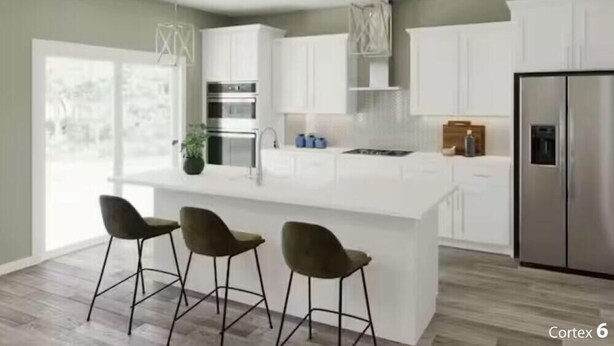 A modern kitchen with white cabinetry, a central island with bar stools, stainless steel appliances, and a large window providing natural light. - Masters Week Retreat (Grovetown)