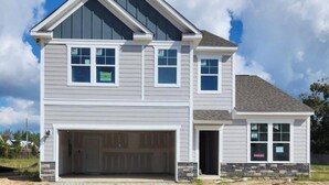 A two-story house with a garage, a stone foundation, and a clear blue sky. - Masters Week Retreat (Grovetown)