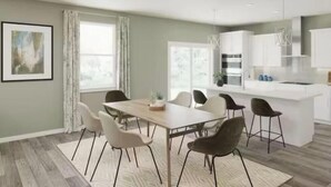 A modern kitchen with white cabinets, a central island, and a dining area with a table and chairs. - Masters Week Retreat (Grovetown)
