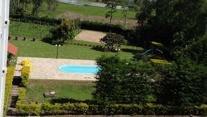 A residential area with a swimming pool, a fenced garden, and a road in the background. - park hotel morotin (Santa Maria)