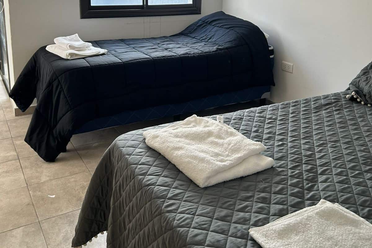 A bedroom with two beds, a window, and a door.