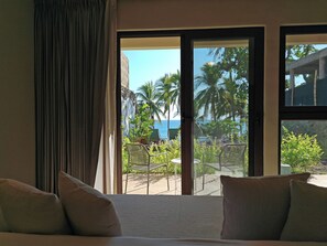 Une chambre d’hôtel avec un lit, une vue sur l’océan et un balcon agrémenté de chaises et de plantes.