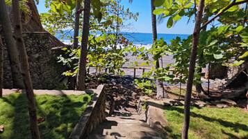 A stone staircase leading to a beach with palm trees and a clear view of the ocean.