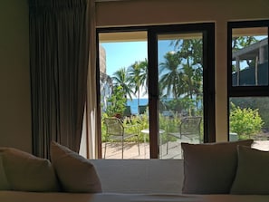Ein Hotelzimmer mit Bett, Meerblick und einem Balkon mit Stühlen und Pflanzen.