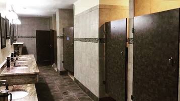 Des toilettes publiques dotées de plusieurs lavabos et de plusieurs cabines, avec des murs et un sol carrelés.