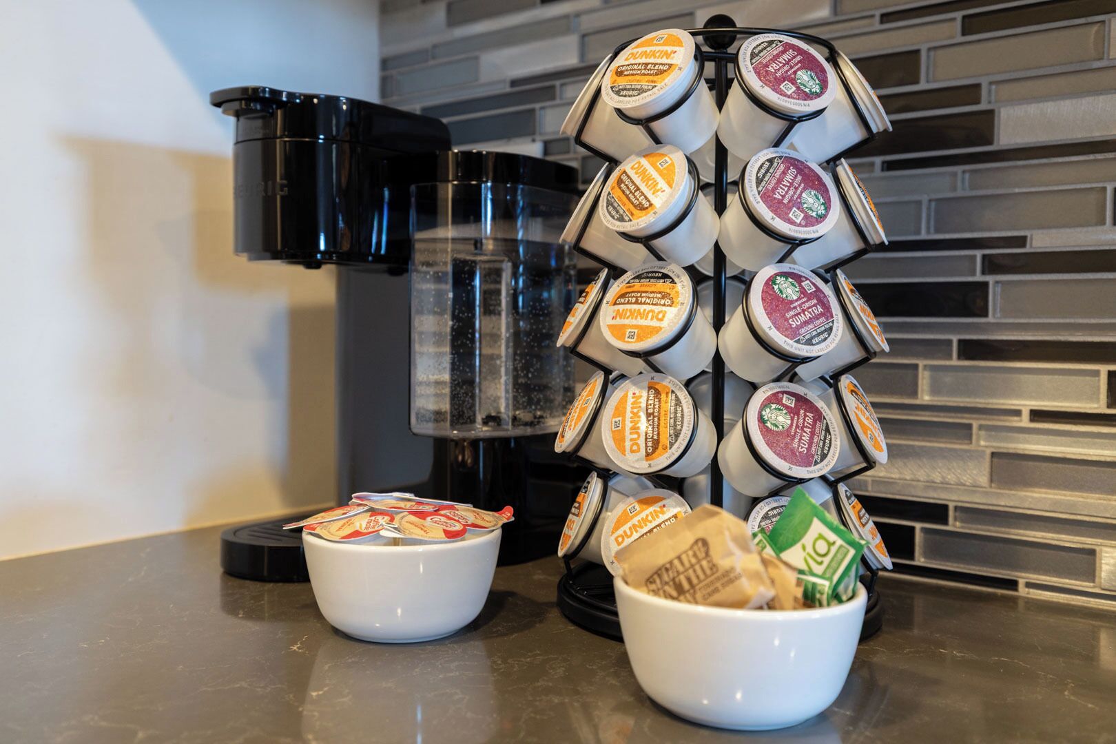 A coffee station with a drip coffee maker and a selection of Dunkin' branded coffee pods.