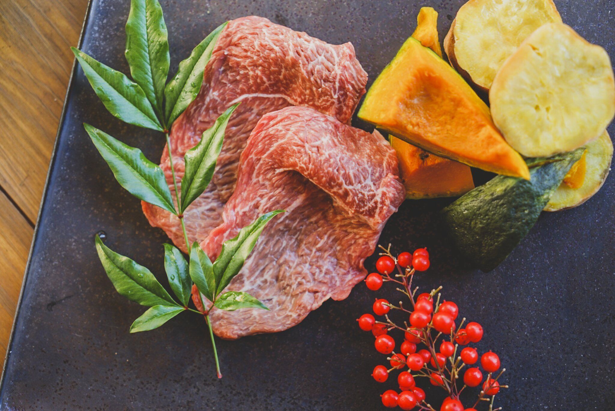 A plate with raw beef, zucchini, and red berries.