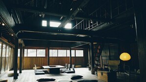 A spacious room with a large table, multiple chairs, and a staircase. - Kominka Yado Loof Sawanoie (Fuefuki)