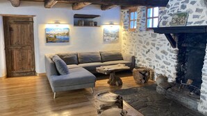 Um interior rústico com lareira de pedra, vigas de madeira, um sofá e decoração rústica.
