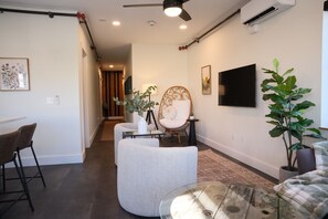 A modern living room with a sofa, armchair, and a glass coffee table. - Brand New 3BR River Condo w/ Large Terrace (Indian River)