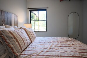 A bedroom with a bed, window, and a wall-mounted mirror. - Brand New 3BR River Condo w/ Large Terrace (Indian River)