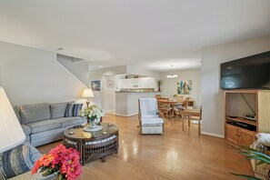 A spacious living room with a sofa, coffee table, and a dining area with chairs and a table. - Three BR Townhome in Sea Colony (Bethany Beach)
