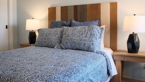 A bed with patterned bedding, a wooden headboard, and two bedside lamps.