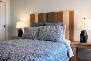 Un lit avec une literie à motifs, une tête de lit en bois et deux lampes de chevet.