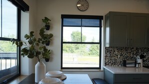 A kitchen with a large window, a clock, and a potted plant.